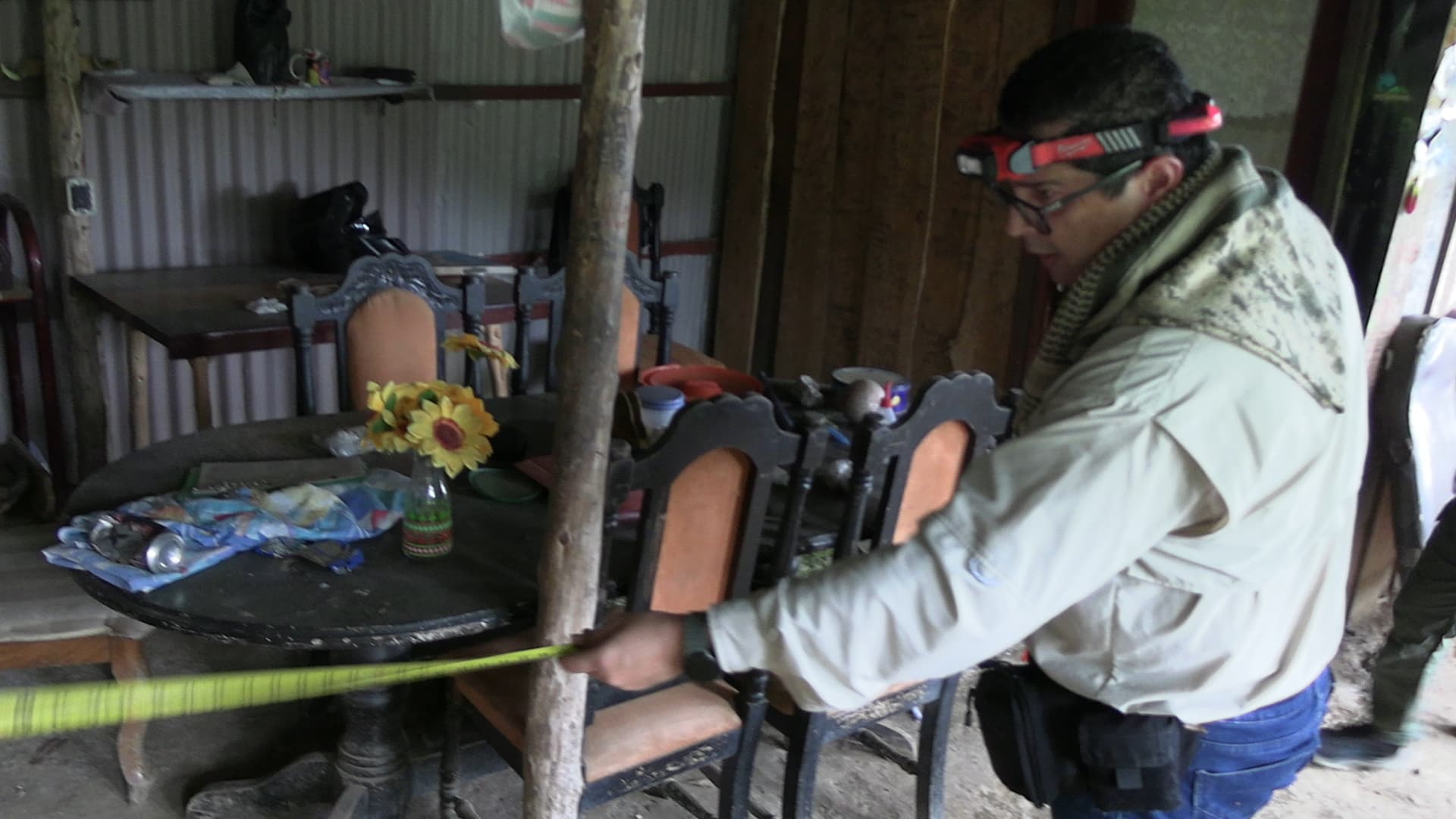 Investigador midiendo la escena del crimen en el interior del restaurante Finca Lajas Alajuelita durante reconstrucción oficial de hechos — caso doble homicidio Toño Badilla Maureen Molina — cinta métrica y cinta de precaución — fotografía Carlos Valencia mayo 2026